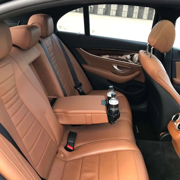 Blick auf die hellbraune Lederrückbank einer Chauffeurlimousine mit zwei Getränken in Getränkehaltern.