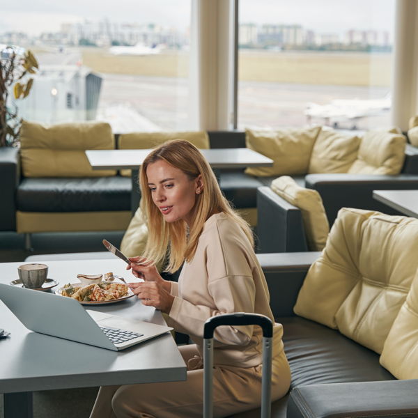 VIP Lounge Flughafen Eine junge Frau mit Laptop sitz in der VIP Lounge am Flughafen Berlin und geniesst ihr Essen.